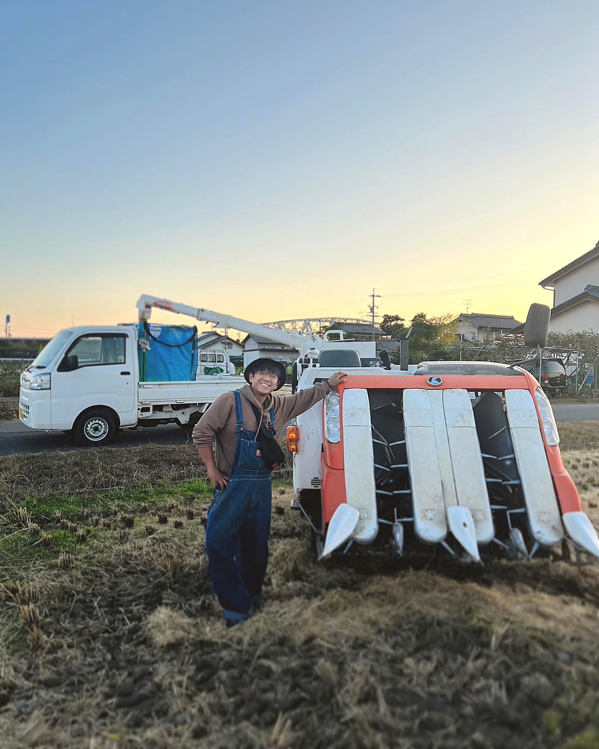 夕暮れの田んぼ、収穫を終えて立つ丸恵商会の代表